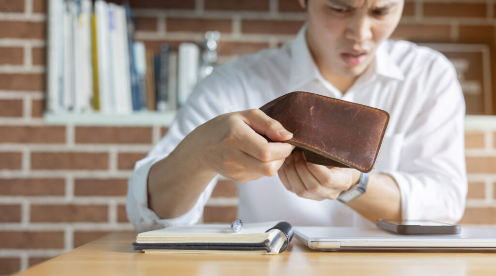Person with no health insurance looking at an empty wallet