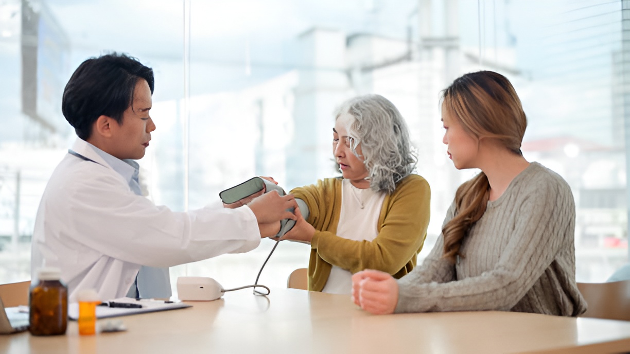 Doctor measuring an elderly woman's blood pressure during a preventive healthcare screening with a family member present.