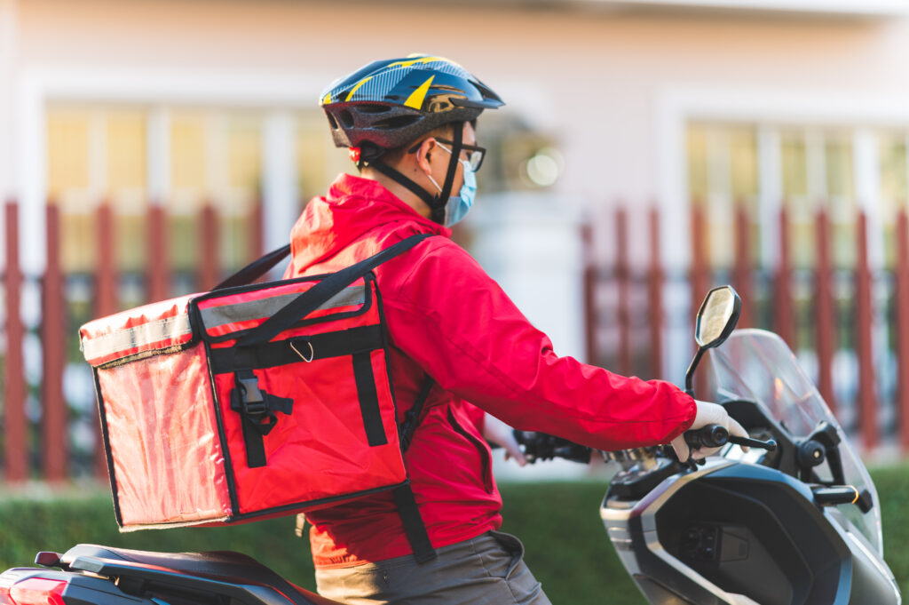 Penunggang penghantaran dengan beg delivery yang mempunyai Insurans Kesihatan