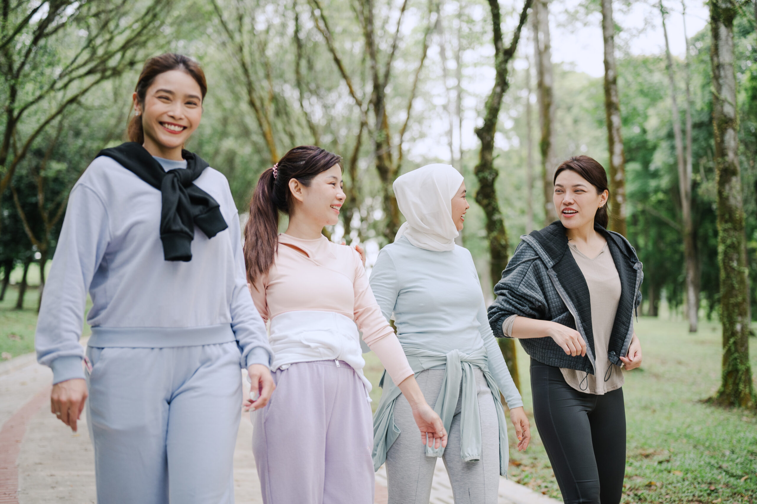 Four women walking together in a park to stay active and manage cholesterol levels
