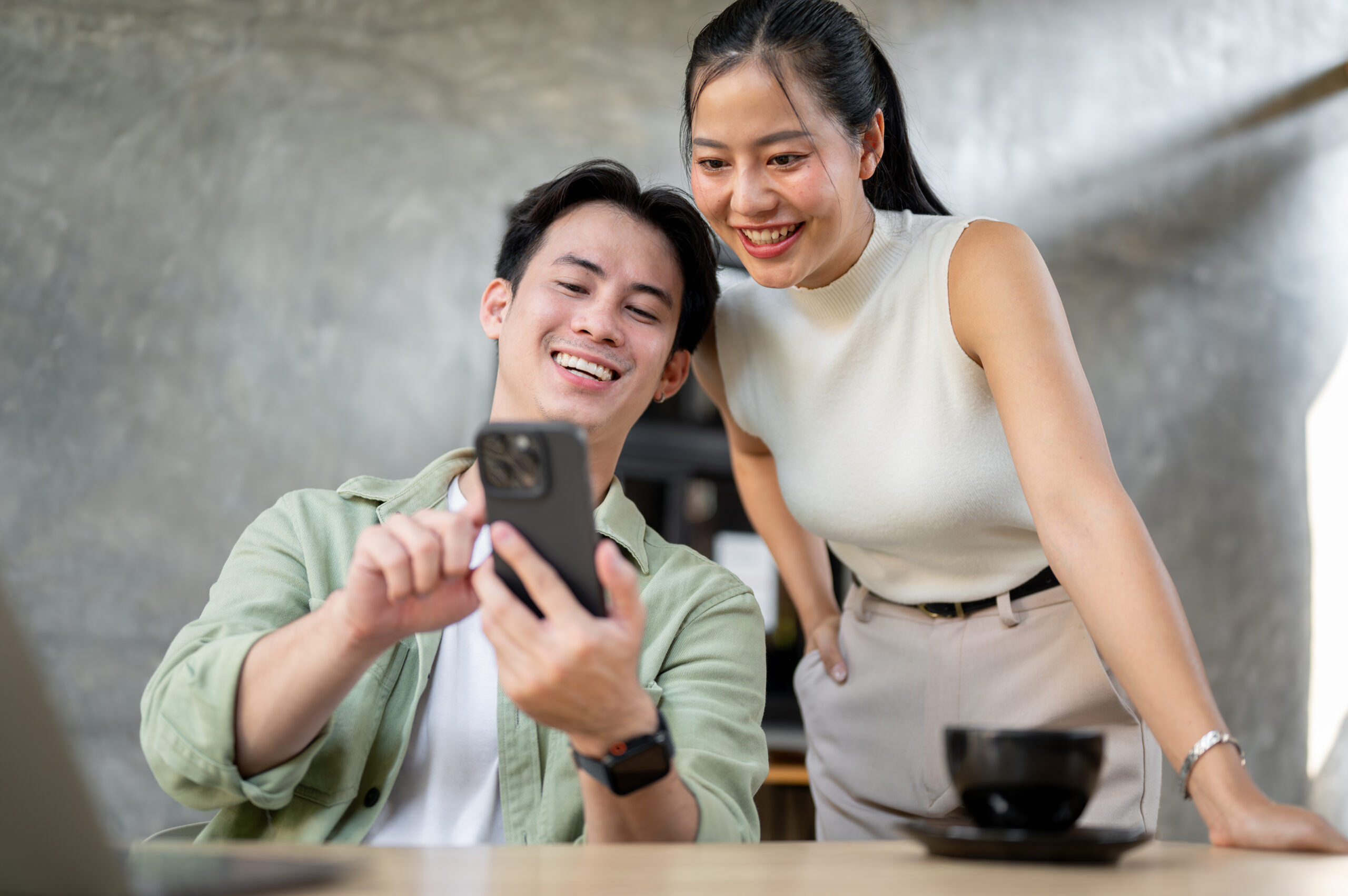 Young couple smiling while reading Malaysia vaping ban news on a smartphone