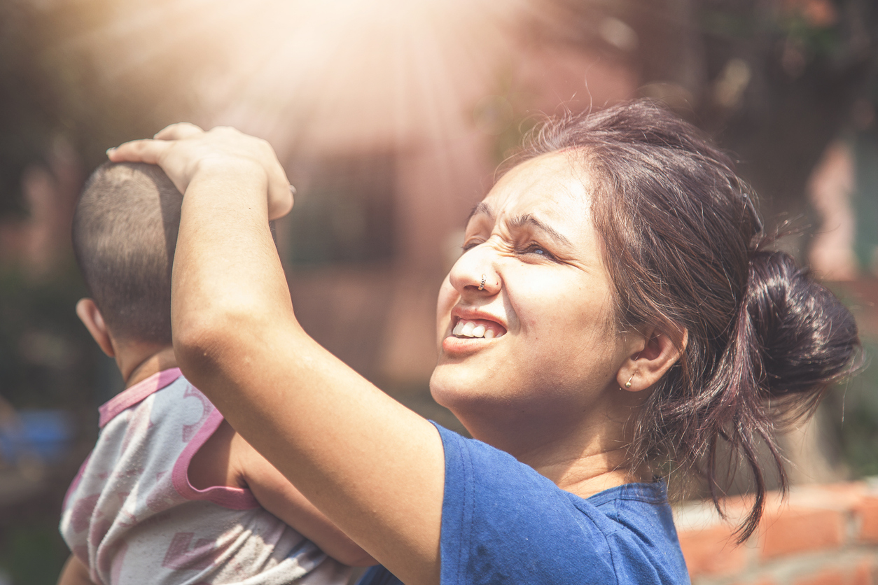 Woman shielding baby from heat and sunlight during a heatwave