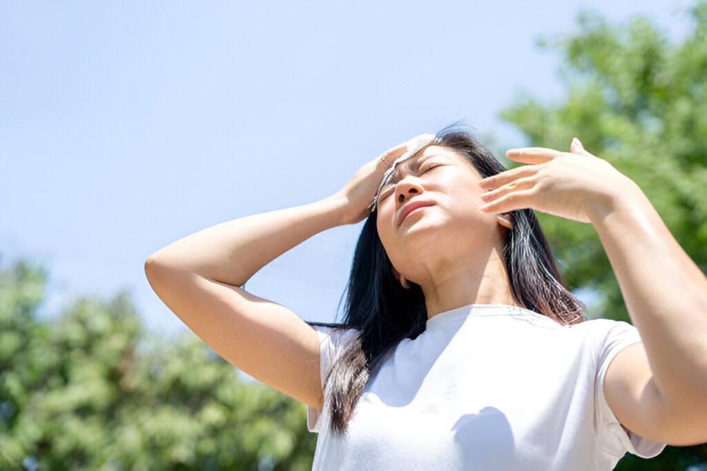 Woman looking tired while wiping sweat under the sun.