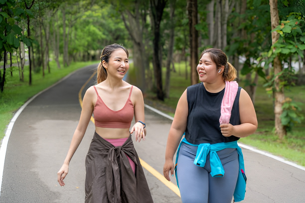 Two women walking side by side during outdoor exercise for metabolic health