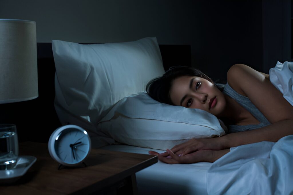 Woman awake in bed struggling with sleep at night.