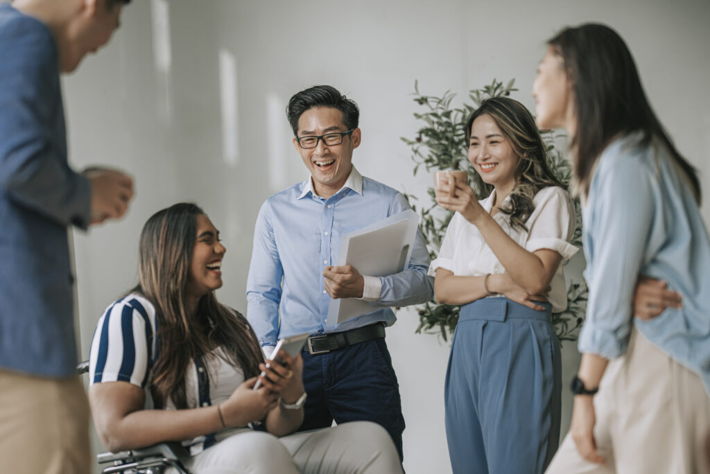 Team of colleagues laughing and chatting together in the office, an example of engaged employees avoiding quiet quitting