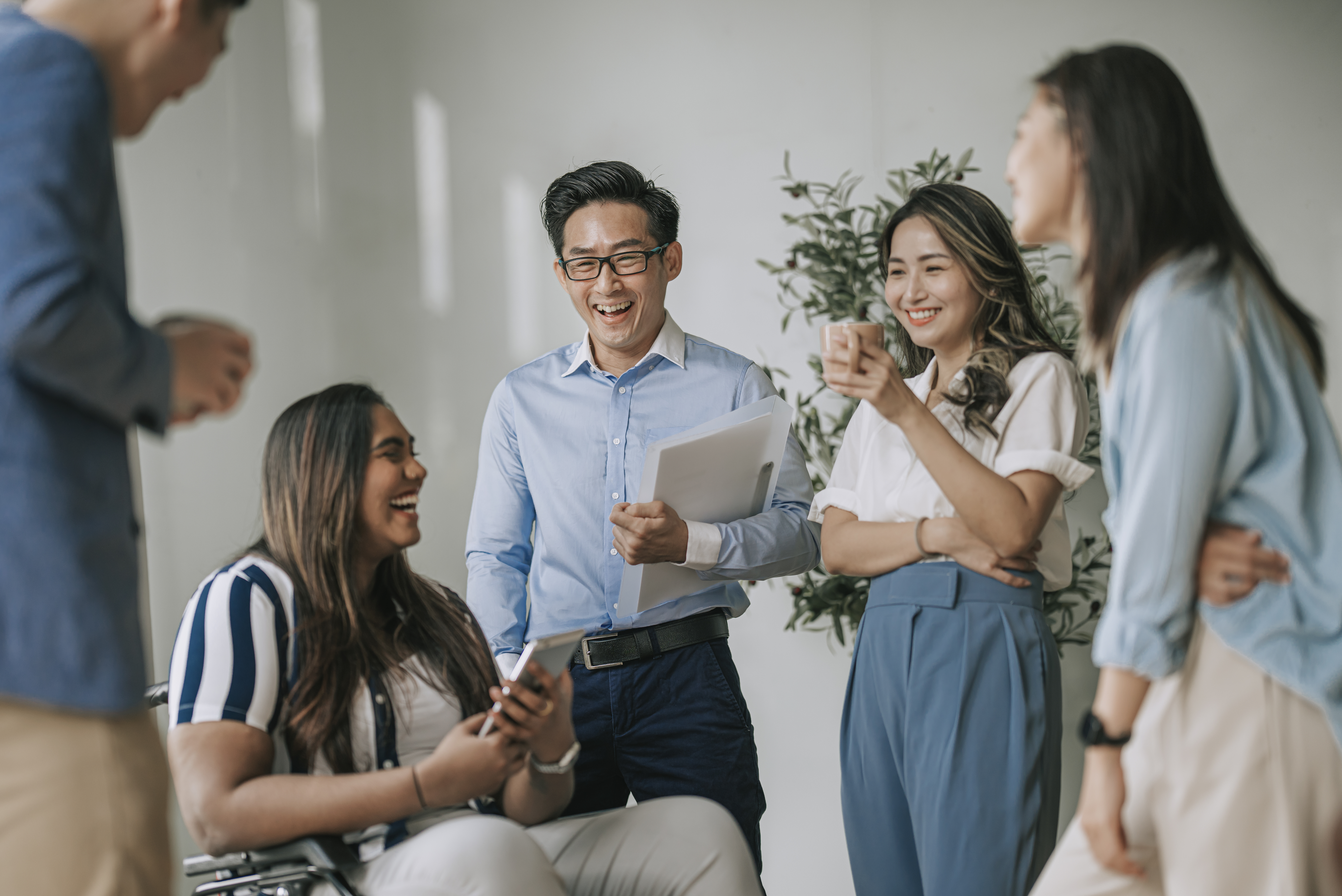 Team of colleagues laughing and chatting together in the office, an example of engaged employees avoiding quiet quitting