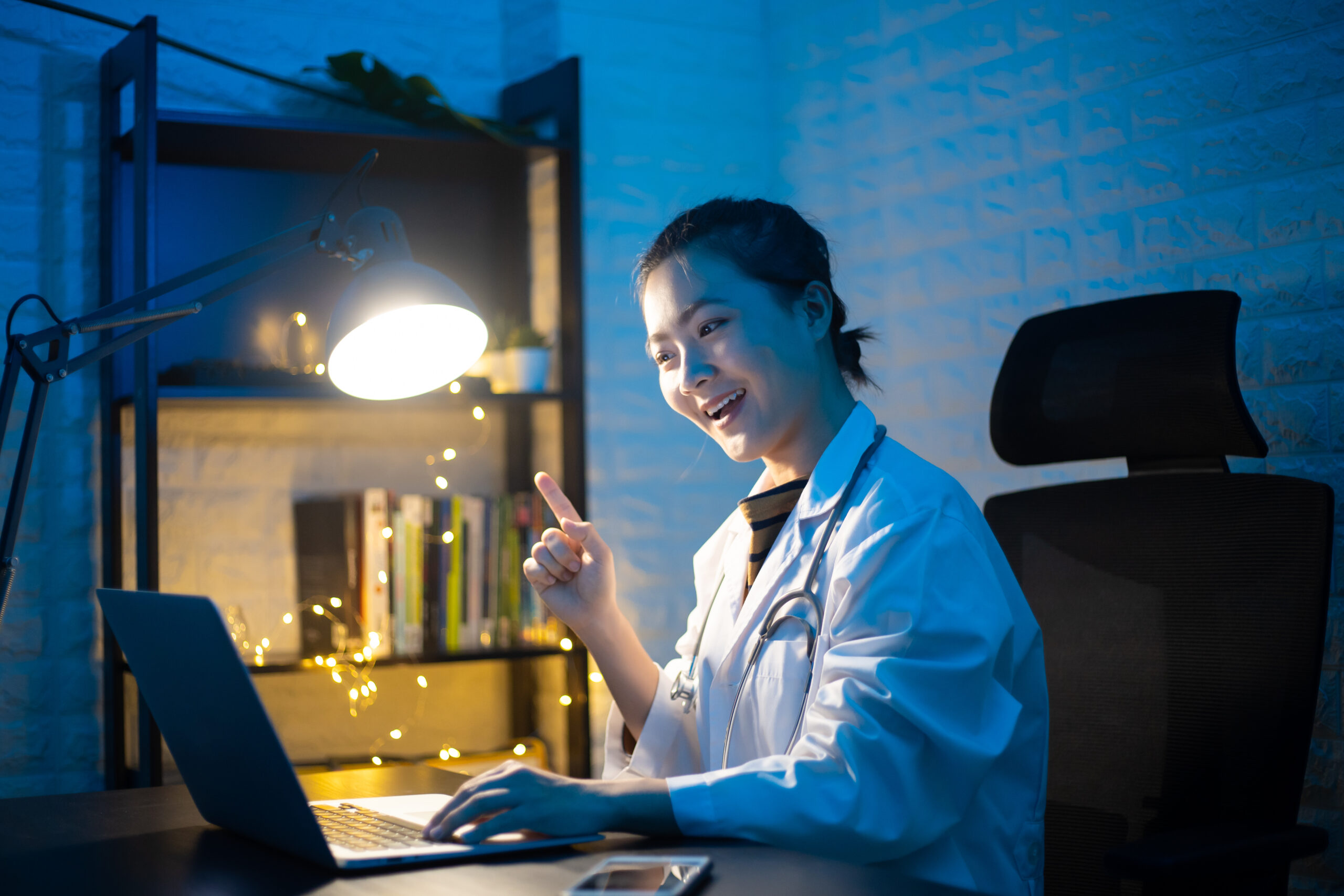 A doctor having an online video consultation from a laptop at night