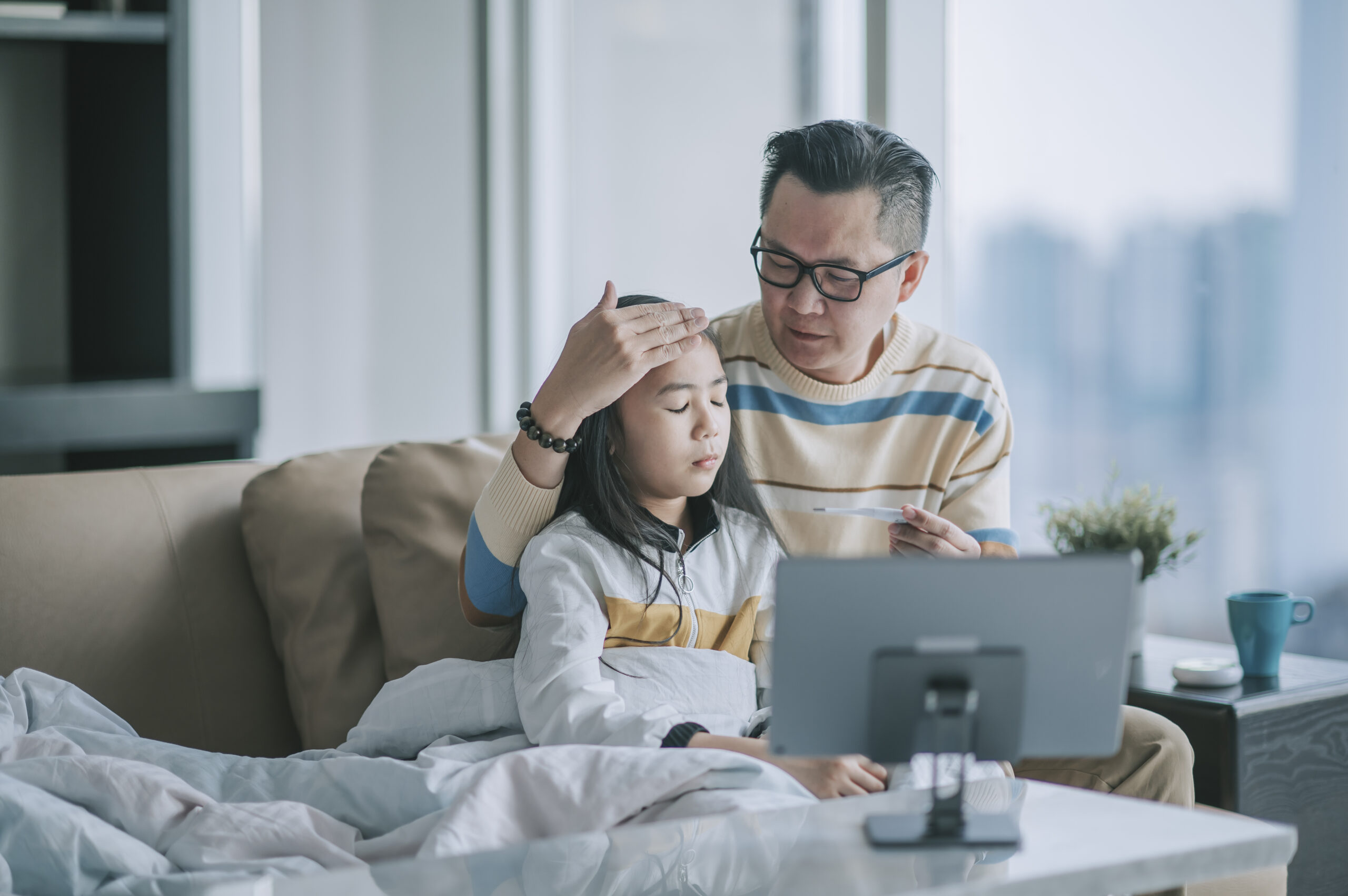 Father checking his sick daughter's fever as part of family healthcare