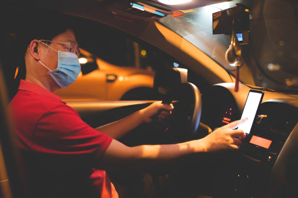 Gig workers using a smartphone while driving at night.