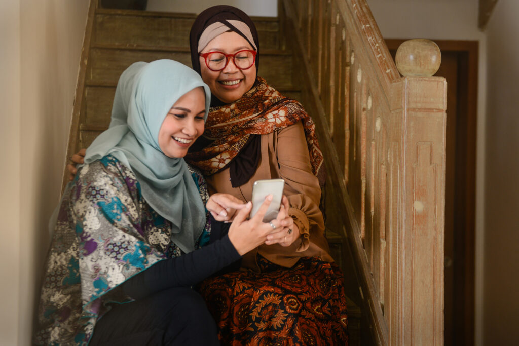 Dua wanita bertudung menggunakan aplikasi kesihatan pada telefon