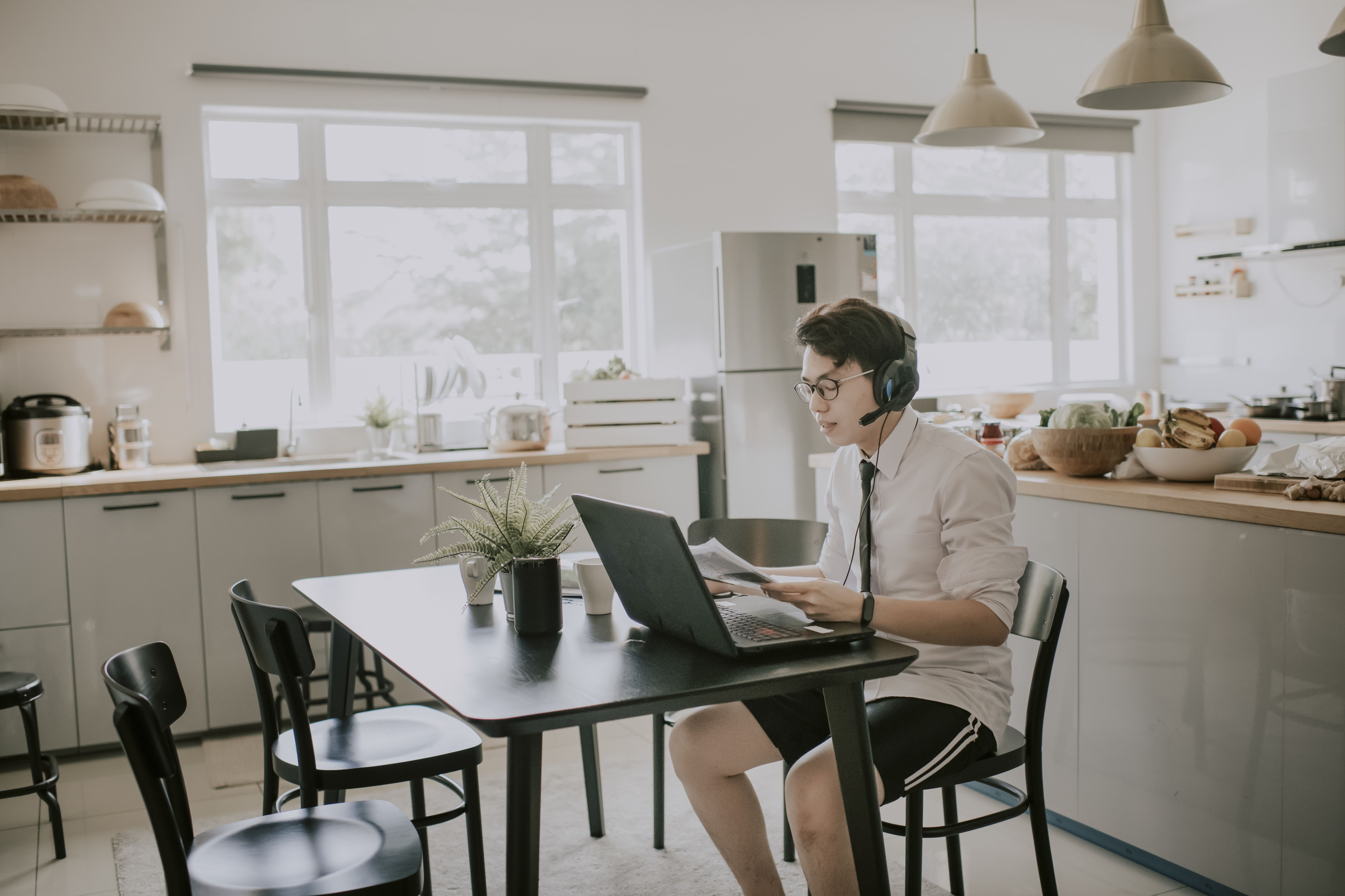 A man working on a laptop with a headset at home, highlighting a modern workplace setup