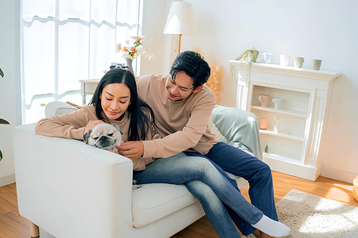A couple at home with their pug, thinking about healthcare for newlyweds